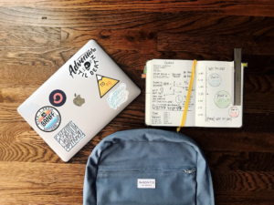 a journal, a bag, and a laptop on a table