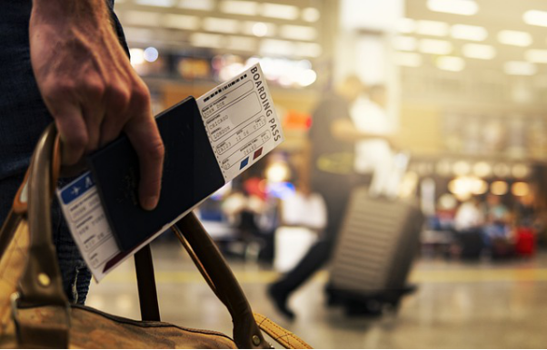 A person at the airport carrying a bag, boarding pass, and passport
