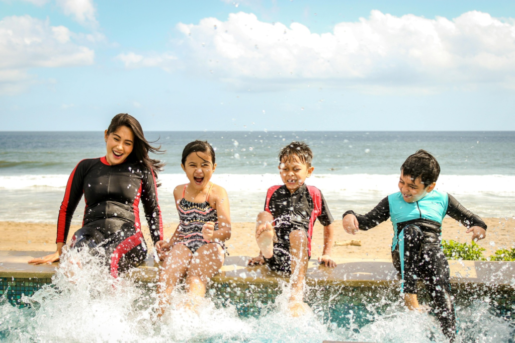 Woman with three kids playing in water